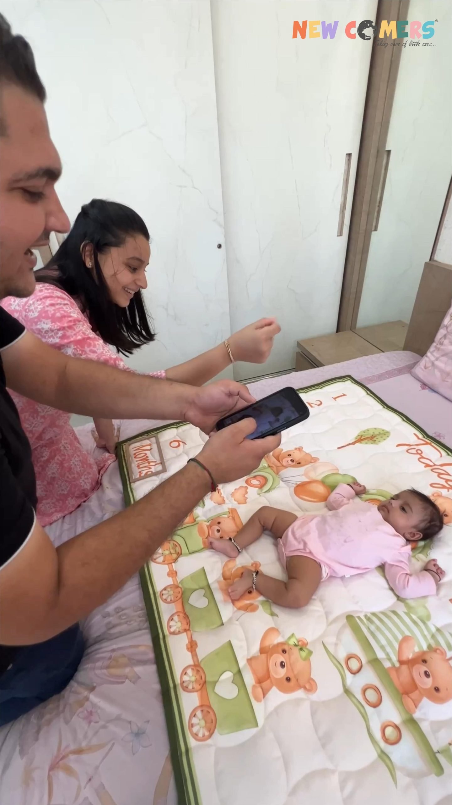 A couple clicking photos of their baby on baby milestone blanket made by newcomers