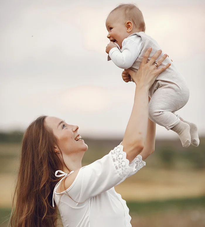 mother holding her baby up with her hand and both smiling