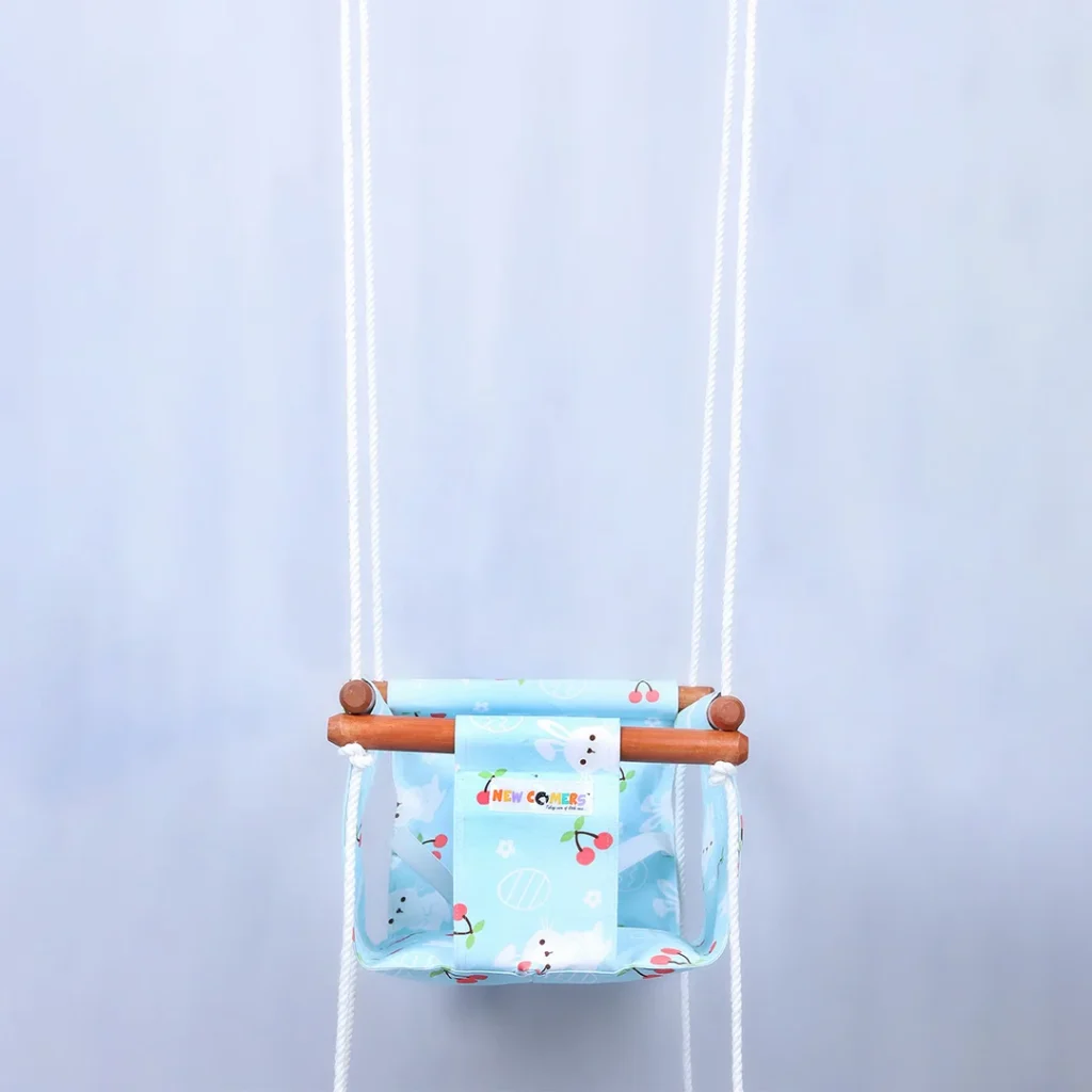 Blue fabric newborn jhula for babies with white rabbit and red cherry prints on it hanging with rope