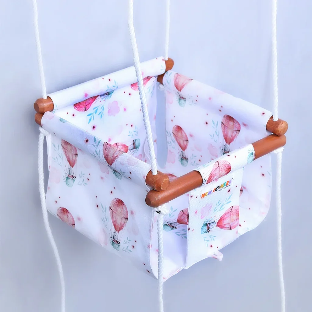 white fabric jhula for babies with small parachute prints, hanging with four ropes passings through wooden jhula frames