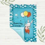 blue fabric rabbit in jumpsuit flying using 3 balloons saying "dream big, little one" newborn mat made by newcomers