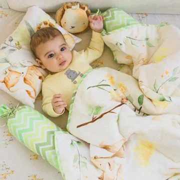 cute baby sleeping inside crib baby blanket set consisting of a soft baby pillow, two bolsters and a organic fleece blanket made by newcomers