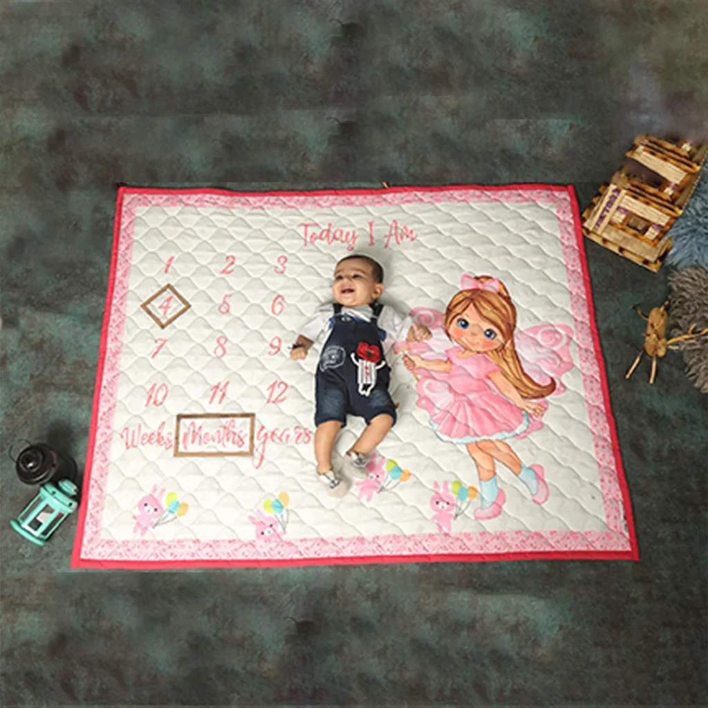 Off white pink fabric new born milestone blanket with a cute girl cartoon print milestone quilt with baby sleeping on it by newcomers