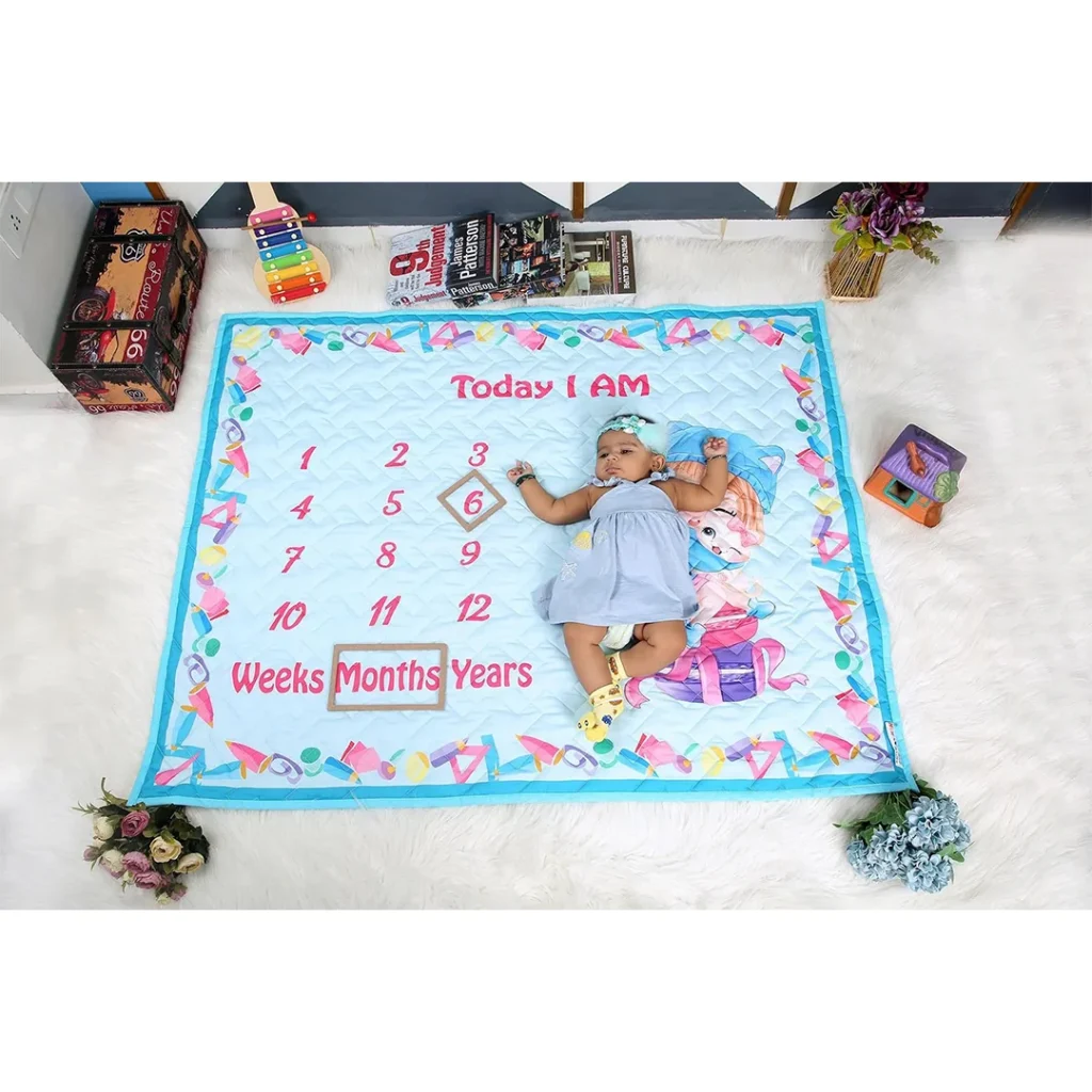 sky blue cartoon prints blanket for newborns with baby girl sleeping on it with props saying she is 6 months old milestone by newcomers